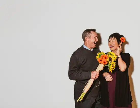 A couple laughing with orange flowers and sunflowers